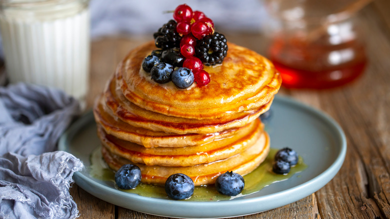 Fluffy golden pancakes dripping with syrup and fruit