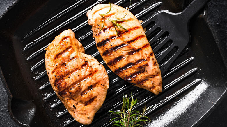 Grilled chicken on pan with spatula and herbs