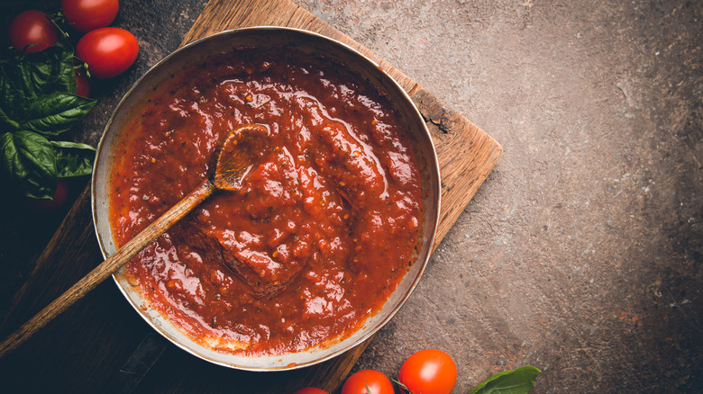 Pot of tomato-based pasta sauce with wooden spoon