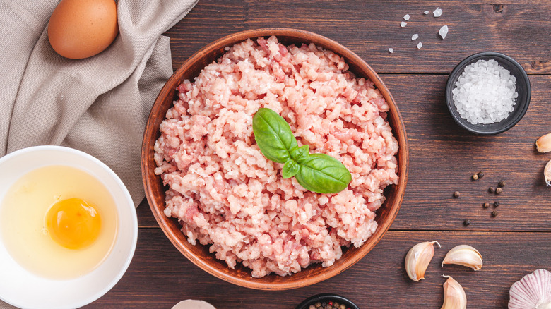 Ground pork in a bowl next to egg, salt, and garlic