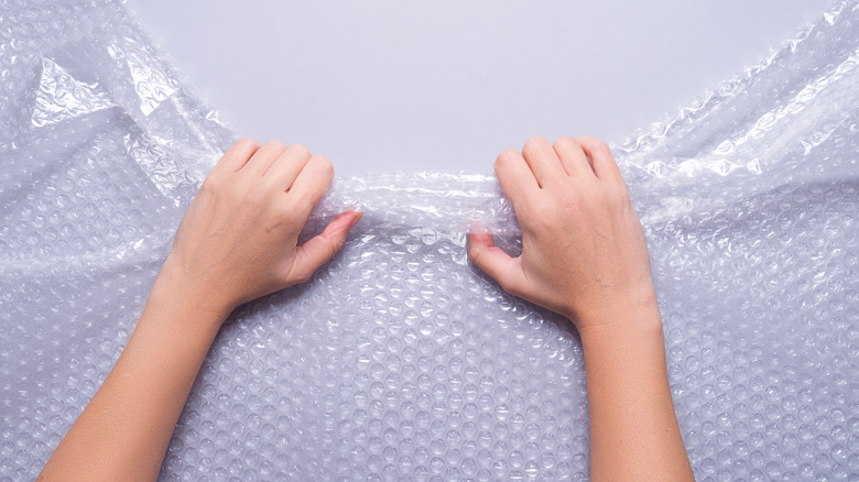 Hands pulling on clear bubble wrap