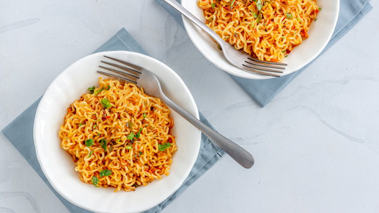 White bowls of ramen instant noodles with forks