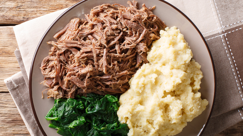 Sadza on plate with shredded meat and greens