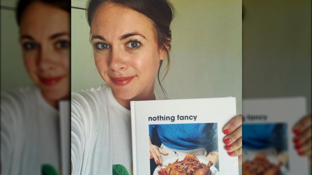 Alison Roman holding a copy of her cookbook