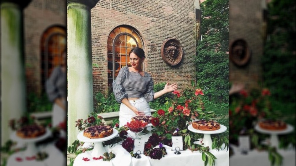 Alison Roman stands behind table full of pastries and flowers