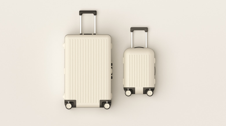 2 white rolling suitcases