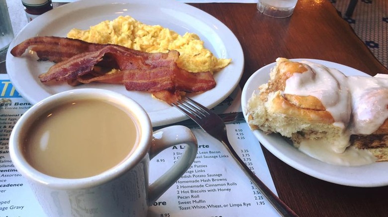 Mug of coffee next to bacon and eggs