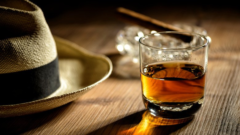 Glass of neat rum next to Cuban hat and cigar