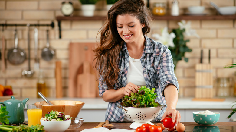 woman cooking in kitchen making salad