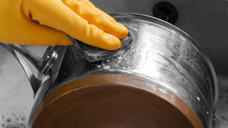 Gloved hand scrubbing pot