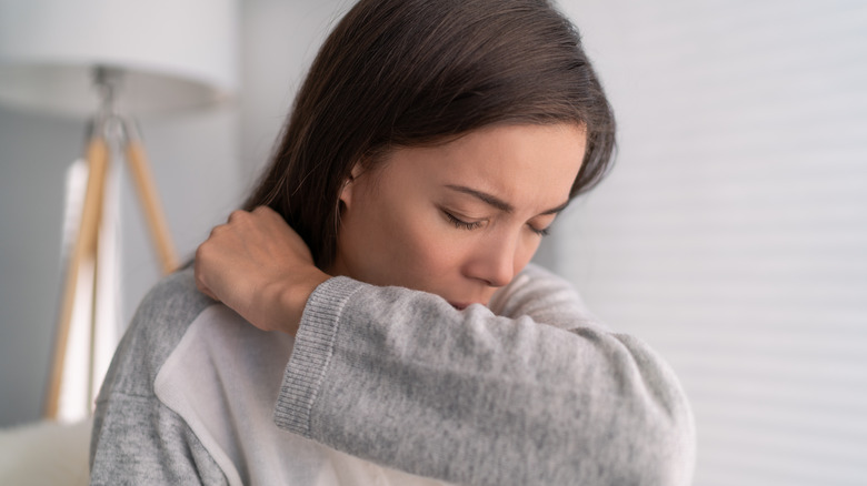 Woman coughing into elbow