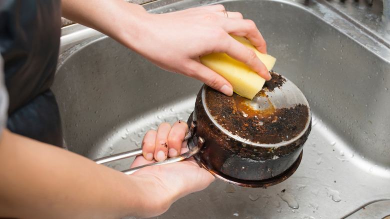 Hand scrubbing tarnished pot