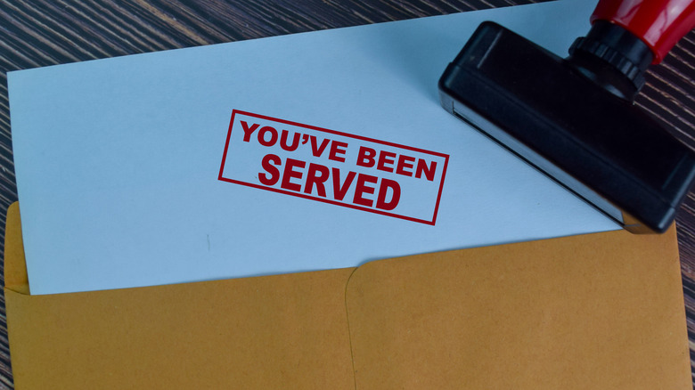 "You've been served" phrase stamped on white paper