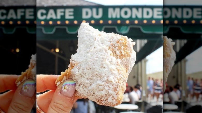 holding up fresh beignet