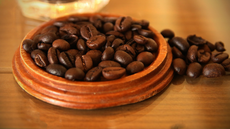 Whole coffee beans in a wooden bowl