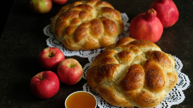 Two round challah loaves, pomegranates, and apples