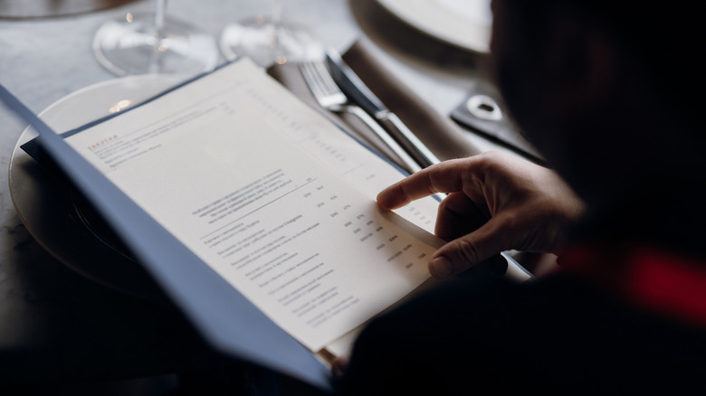 Person reading restaurant menu at a table