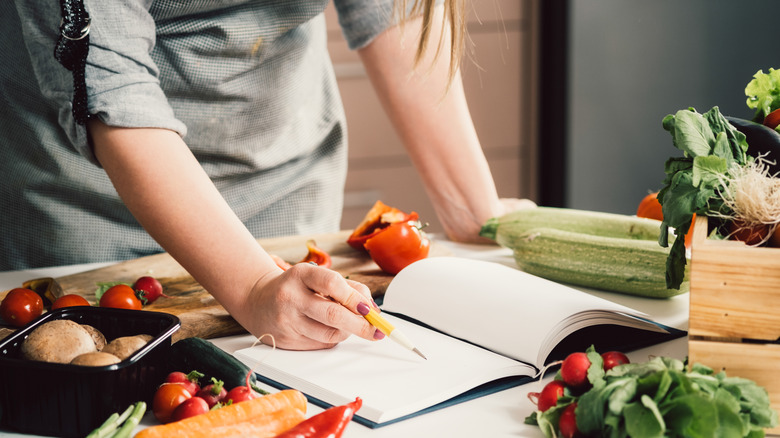 Woman in kitchen reading cookbook