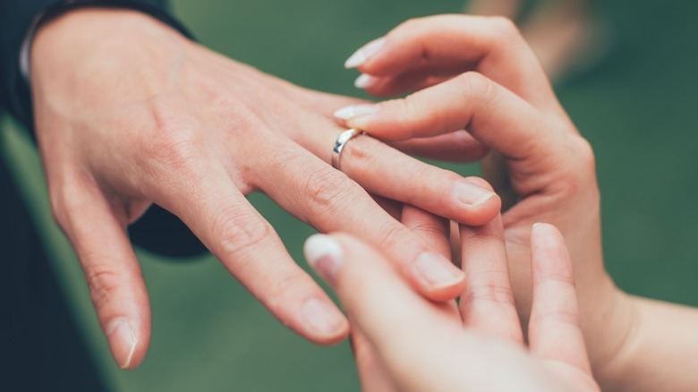 hands putting on wedding rings