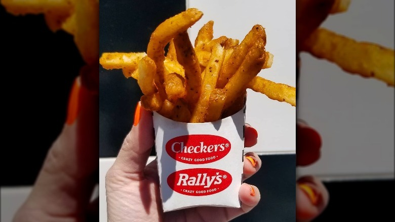 Woman's hand holding checkers rally's seasoned fries