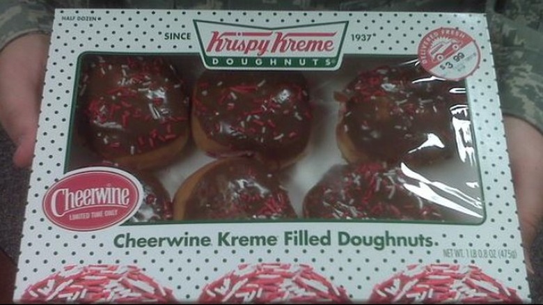 Hands holding box of Cheerwine Krispy Kreme doughnuts