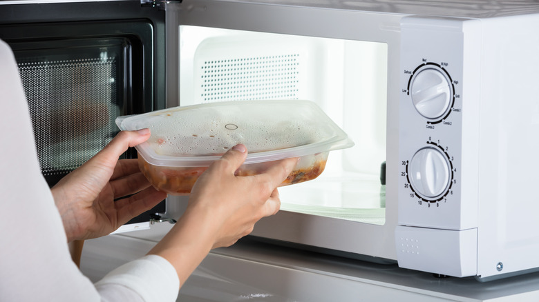 A person using a white microwave