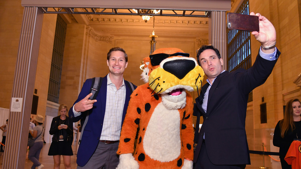 Chester Cheetah posing for a picture with two men