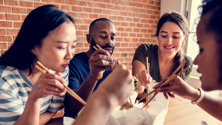 people friends eating chow mein take out