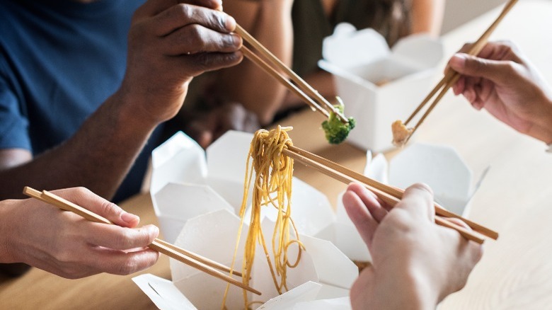 hands chopsticks chow mein noodles