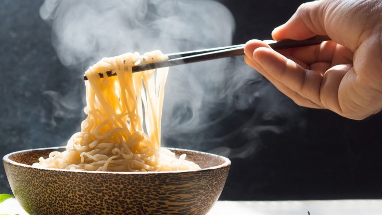 Noodles in bowl hand holding chopsticks