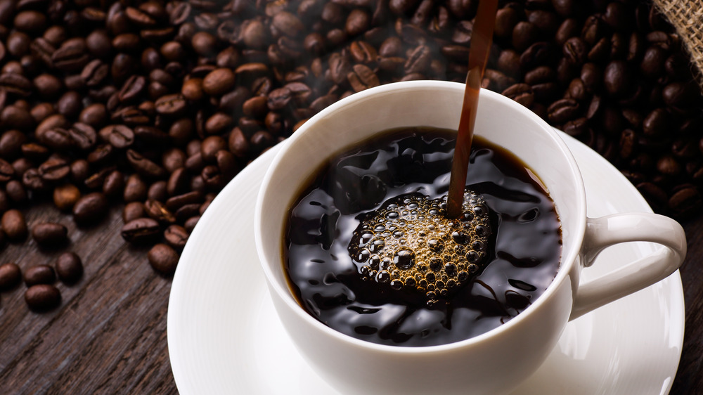 Mug of coffee surrounded by coffee beans