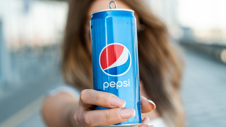 Woman extending Pepsi can forward