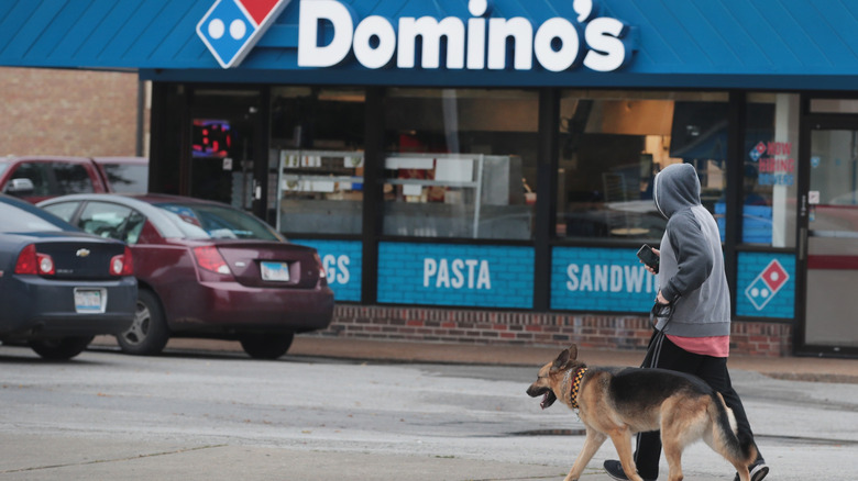 Man walking a dog outside Domino's