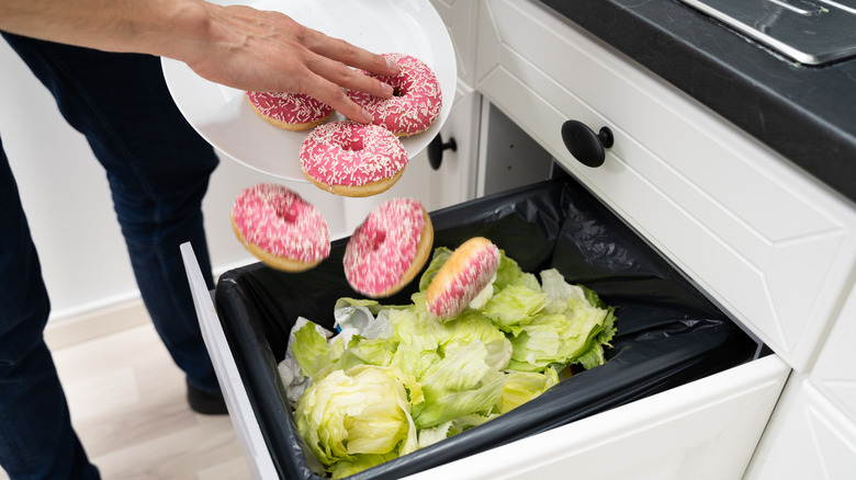 Person throwing donuts in trash