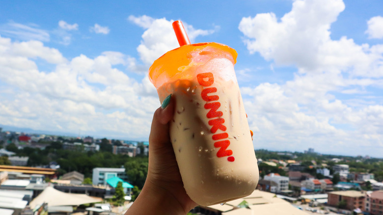 Woman lifting iced coffee to sky