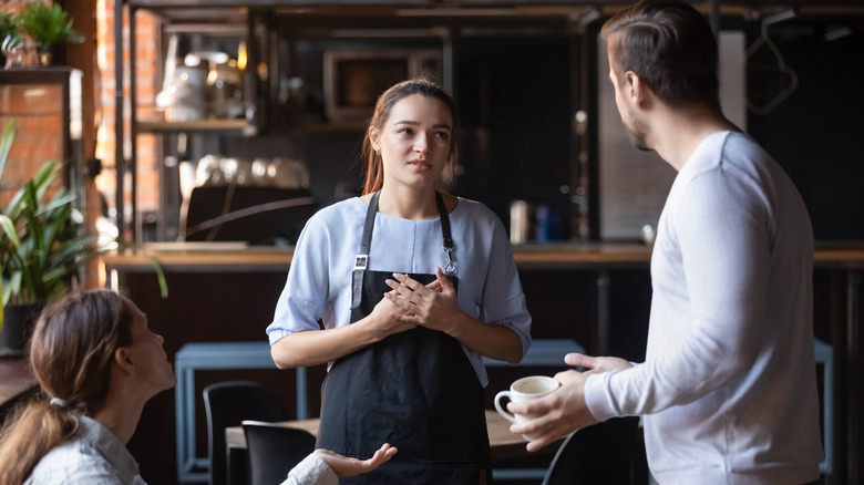 A hostess at a restaurant talking to patrons