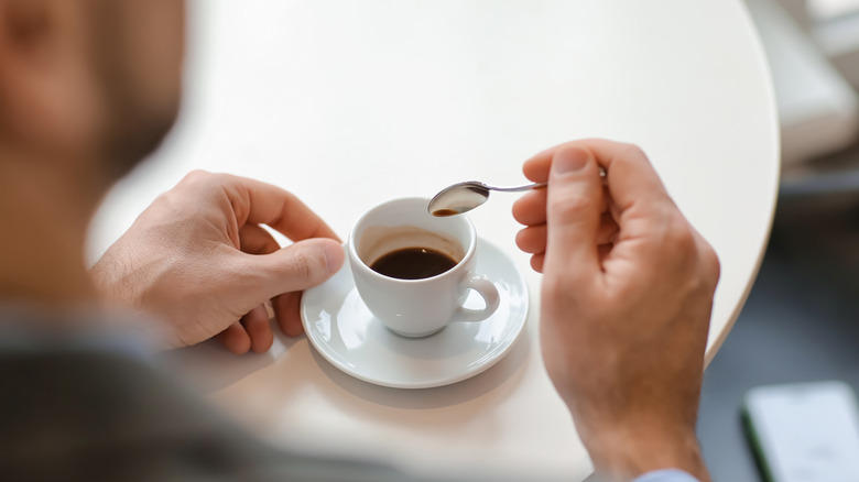  hand with spoon stirring espresso