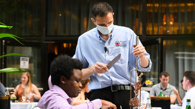 Chef cutting meat at a Brazilian steakhouse