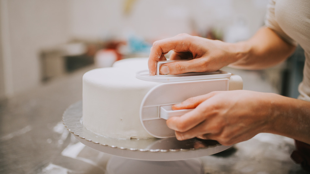 baker wrapping cake in fondant