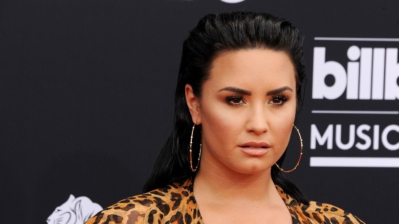 Demi Lovato in leopard print, bangle earrings, and slicked back hair.