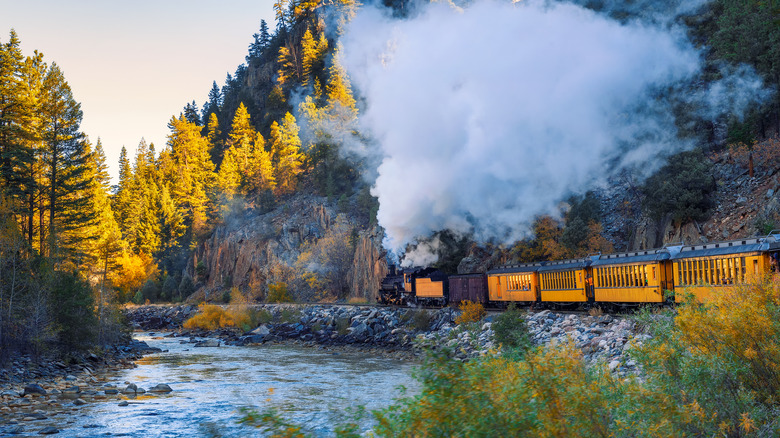 Orange passenger train riding through hills