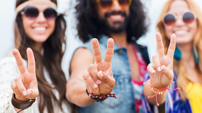 Three hippies giving the peace sign.