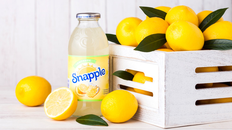 A bottle of Snapple next to a box of lemons.