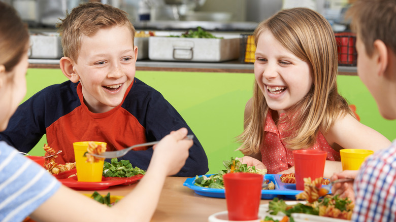 Happy kids eating lunch at school.