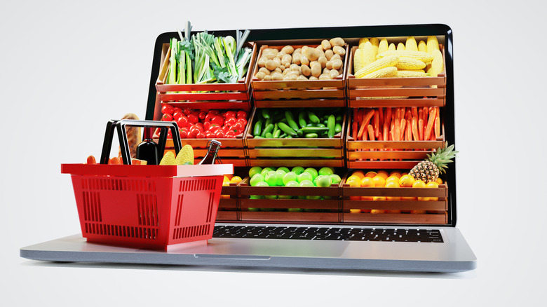 concept art illustrating online shopping with produce bins projecting from laptop screen and full grocery basket resting on keyboard