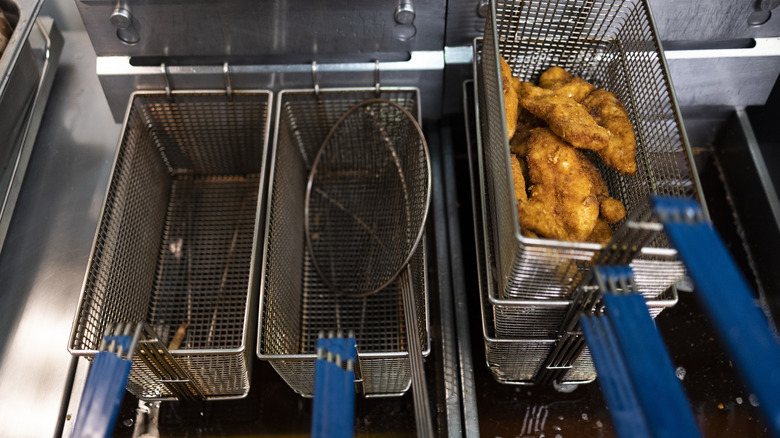 Deep fryer with cooked chicken pieces being removed.