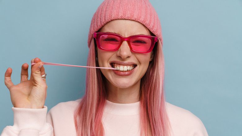 Pink haired woman stretching chewing gum