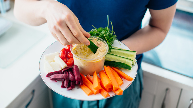 hand dipping vegetables in hummus 