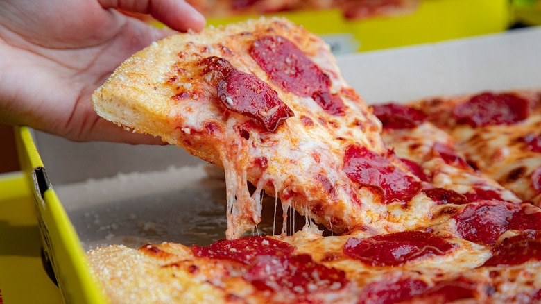 Hand grabbing pizza slice