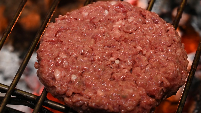 raw burger patty on grill